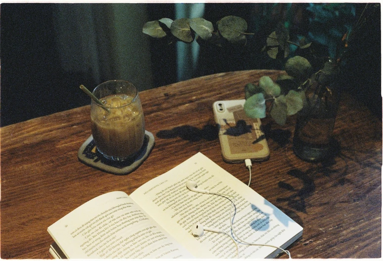 an open book sits beside a glass vase with flowers