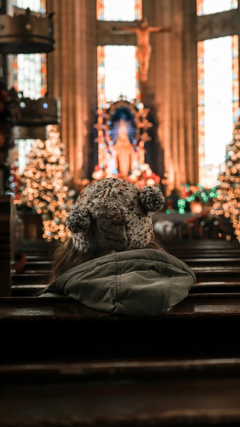 a teddy bear sitting on the pew in a church