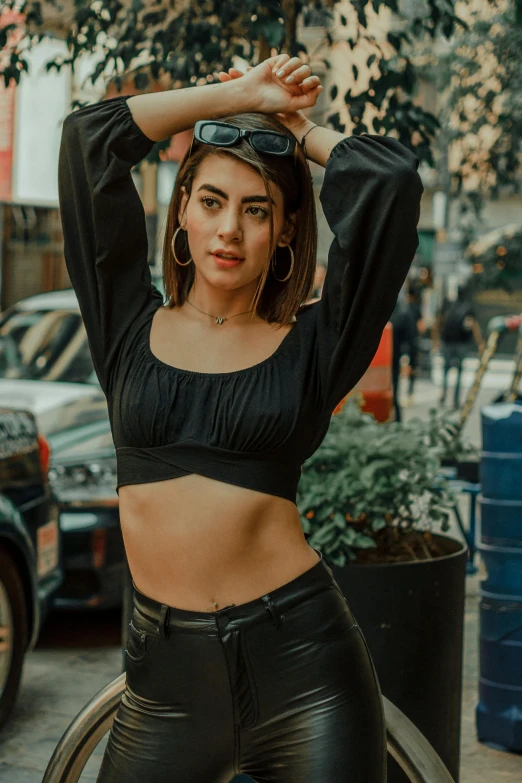 a woman wearing black clothing posing with her hands behind her head