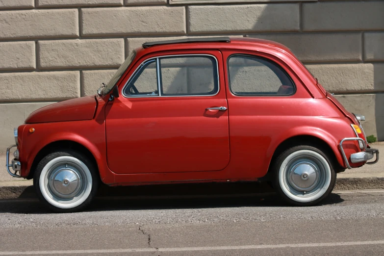 a red car parked in front of a brick wall