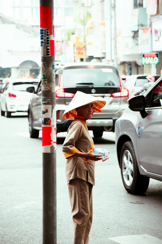 a person in a hat standing under a traffic sign