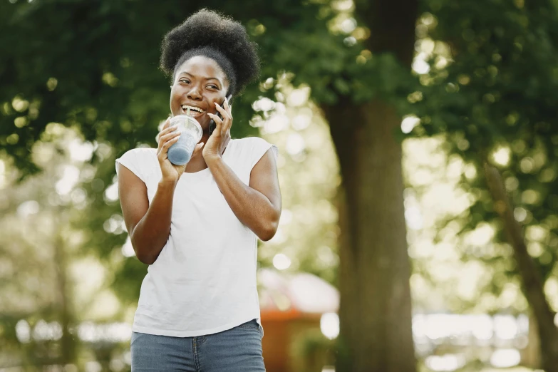 the woman is enjoying a drink while talking on the phone