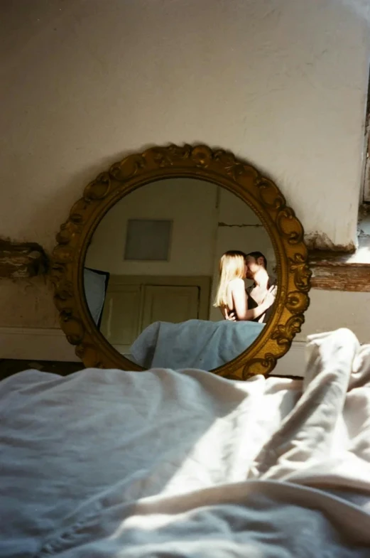 a mirror reflecting a girl on the bed