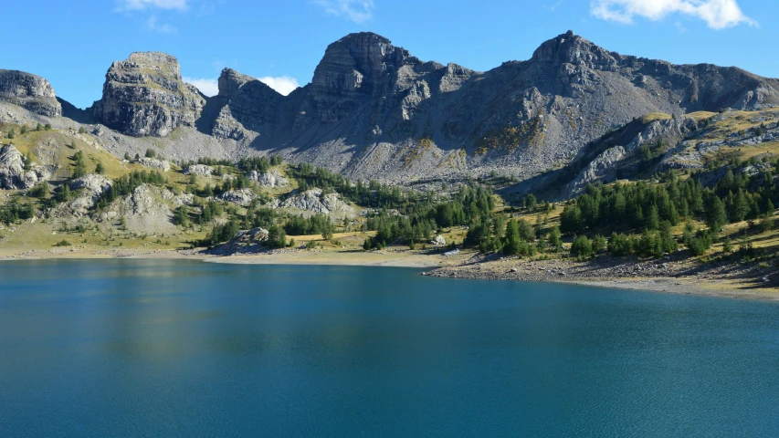 a lake surrounded by mountains under a blue sky