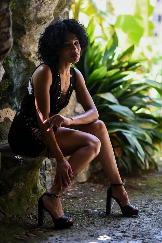 a woman sitting on a stone wall in high heel shoes