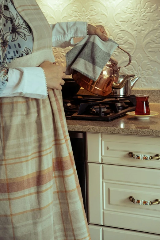 a women standing by a stove while pouring tea