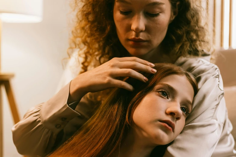 a young woman combs her hair next to an older woman