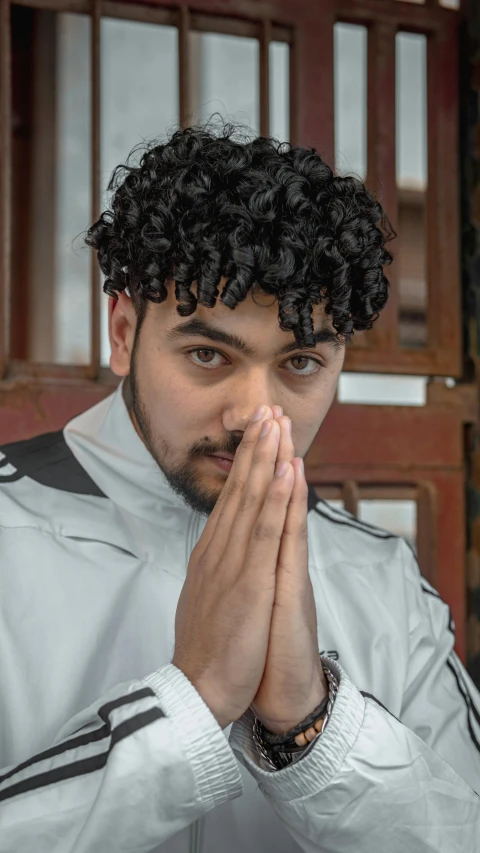 a man with curly hair is holding his hands together