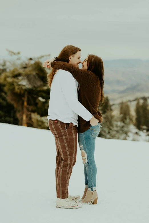 a couple is hugging and sharing a kiss in the snow