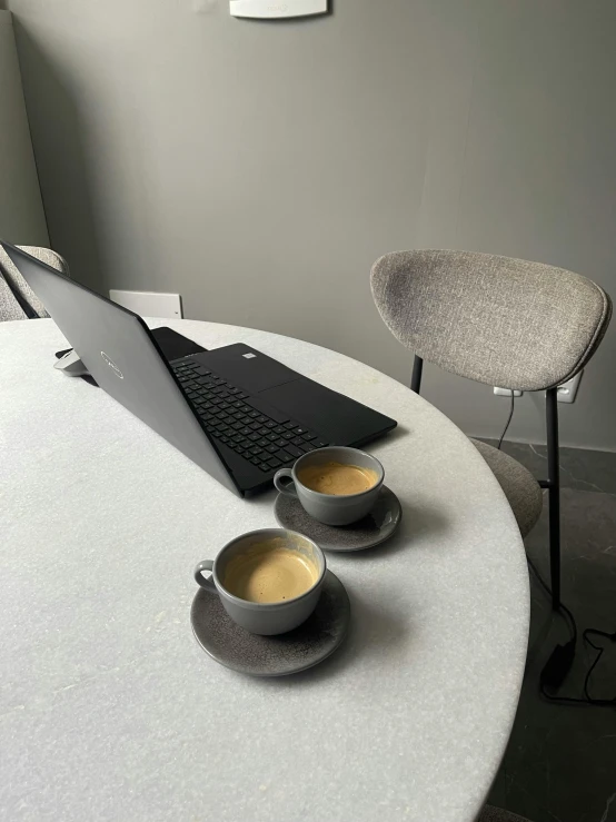 a lap top is on a table in front of coffee cups
