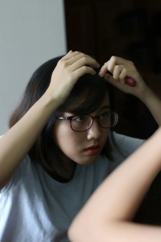 a woman adjusting her hair in a mirror