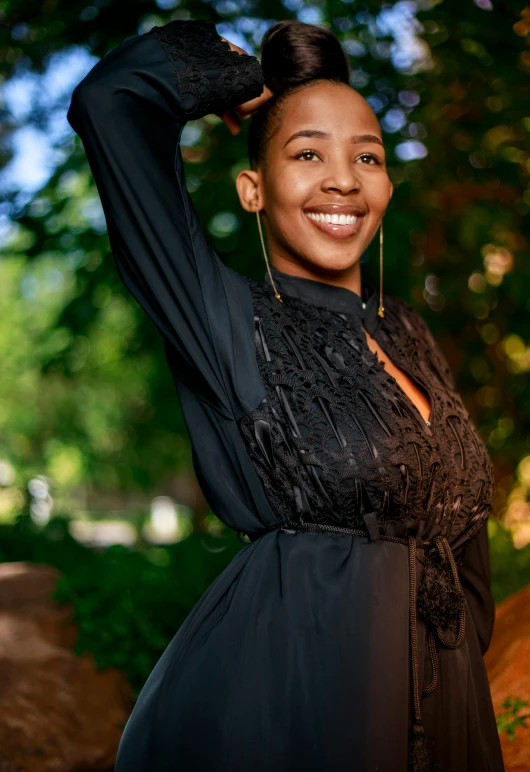 the woman is posing in a black dress with large gold earrings