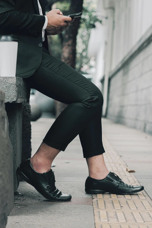 a person wearing black shoes sits on a street bench