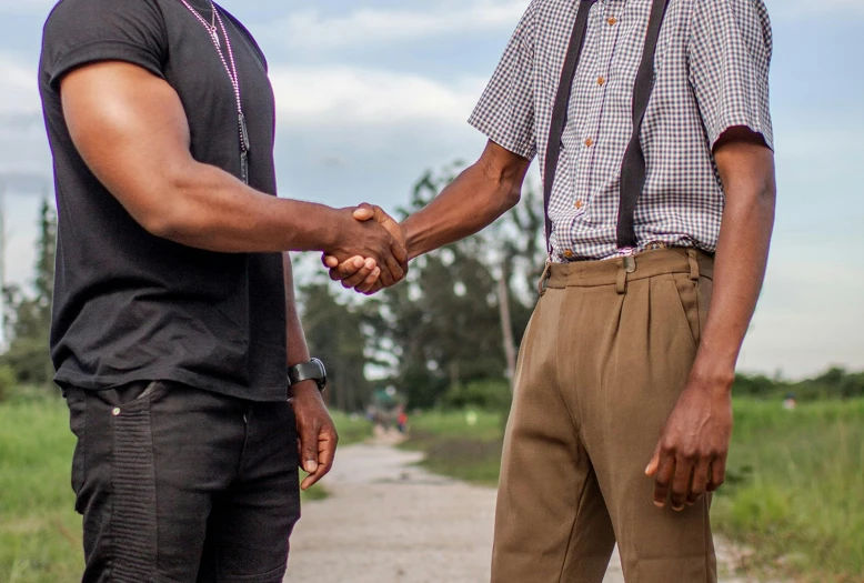 two men talking to each other standing in a park