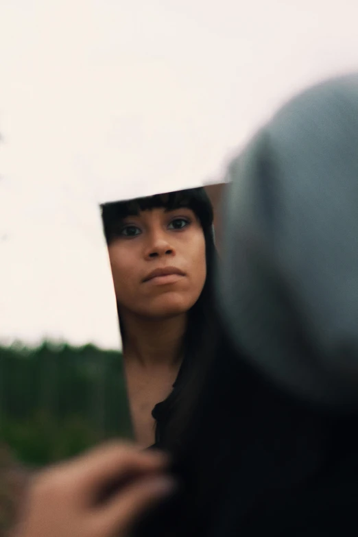 a woman looking out of a large mirror