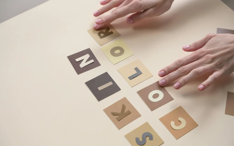 a person reaching down for a tile with letters and hands