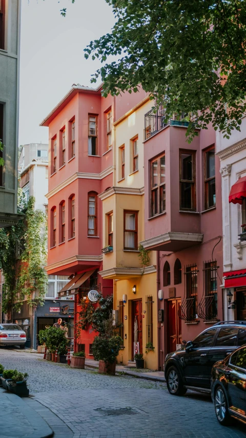 several colorful buildings on the street corner with parked cars and an umbrella on a clear day