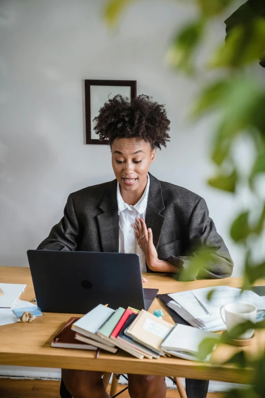 a woman sits at her desk and uses a laptop