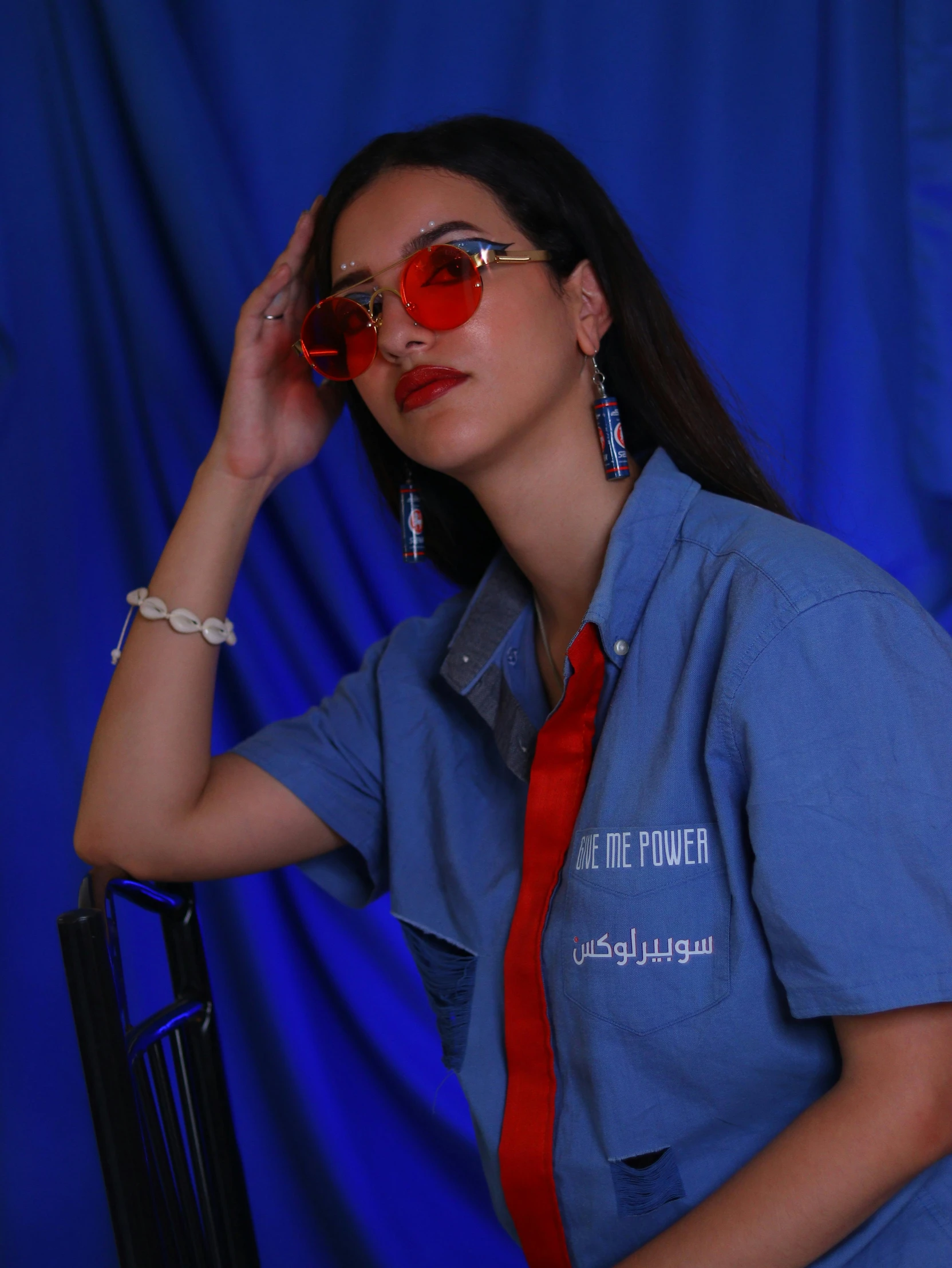 a woman wearing sunglasses, a blue shirt and a red tie