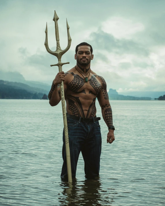 man holding up giant wooden sword in calm water