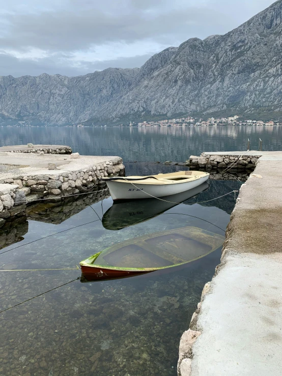 two boats in a harbor surrounded by mountains