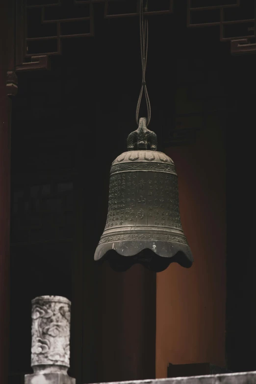 a bell hanging above a marble pillar inside of a building