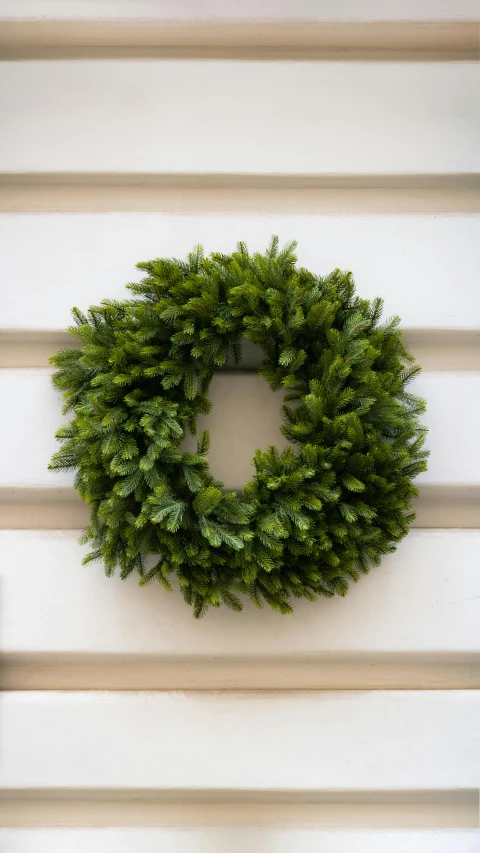 green wreath hanging on wall by brown shutters