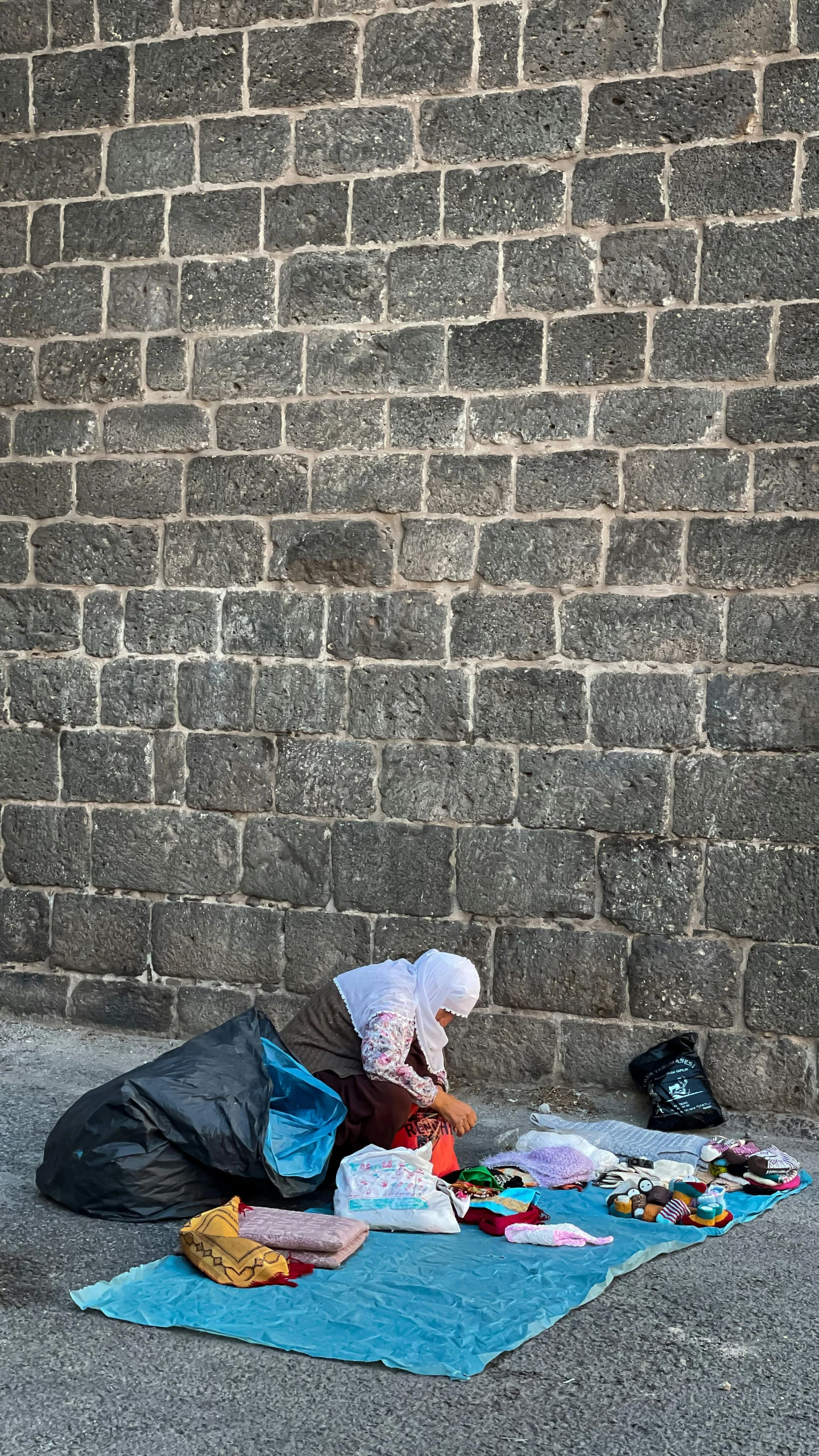 a garbage bag sitting on the sidewalk with cloth strewn around it