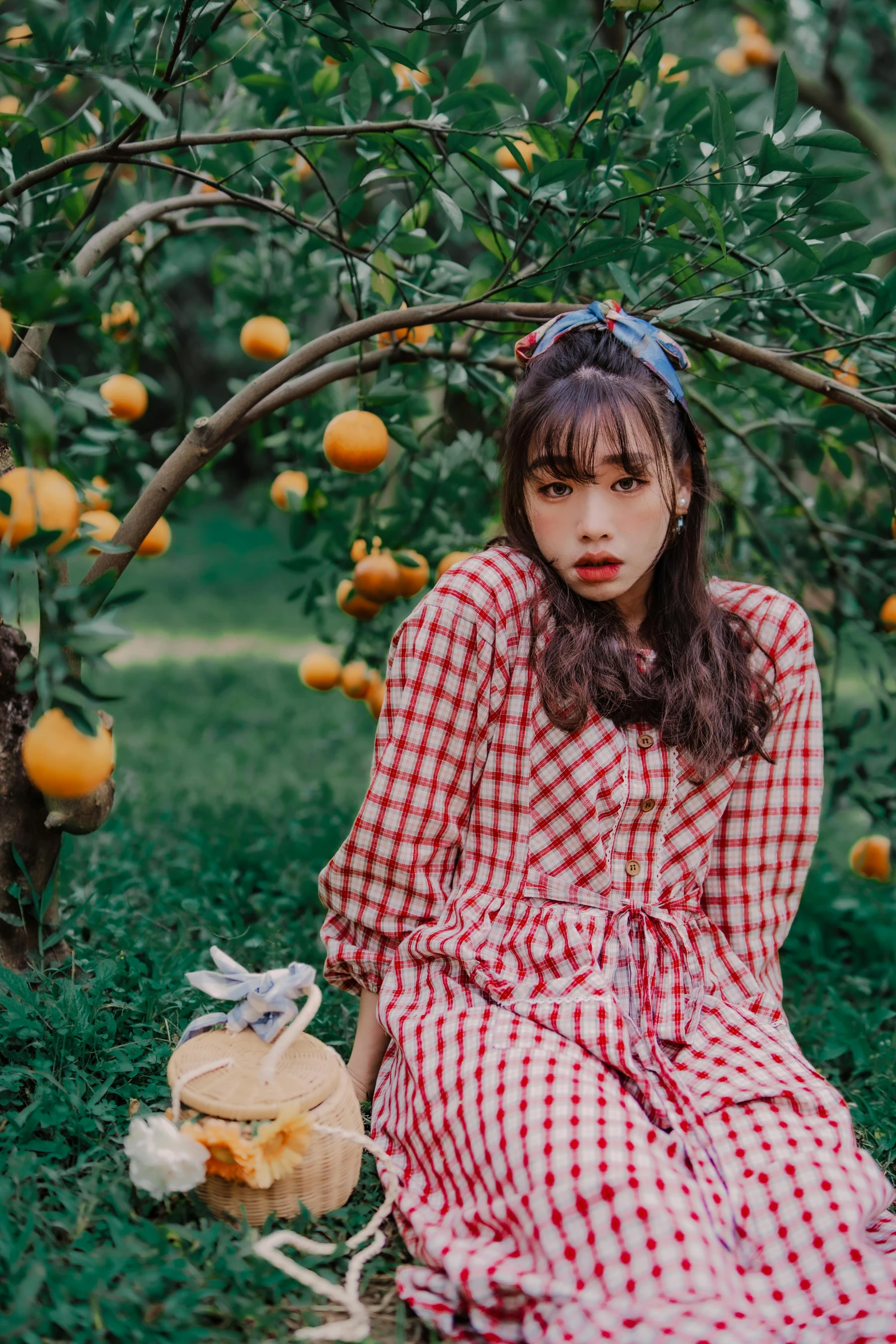 a girl is sitting next to an orange tree