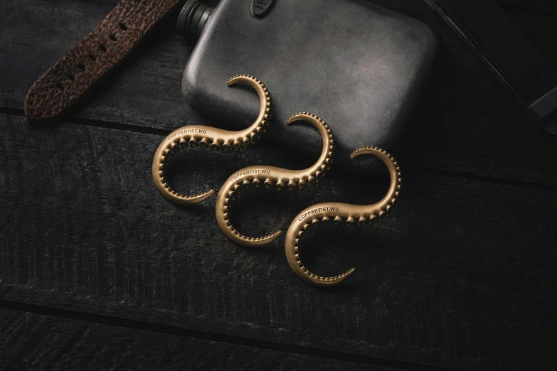 two golden octo shaped rings sit on top of a black surface