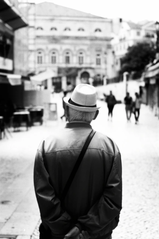 a man in a hat is standing on the sidewalk