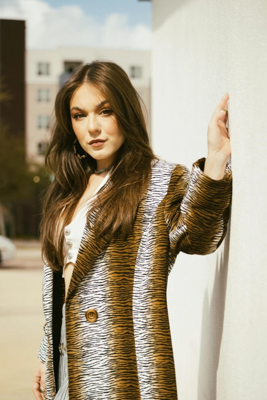 a beautiful young woman posing by a wall