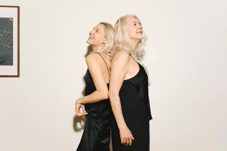 two women dressed in black dresses standing next to each other