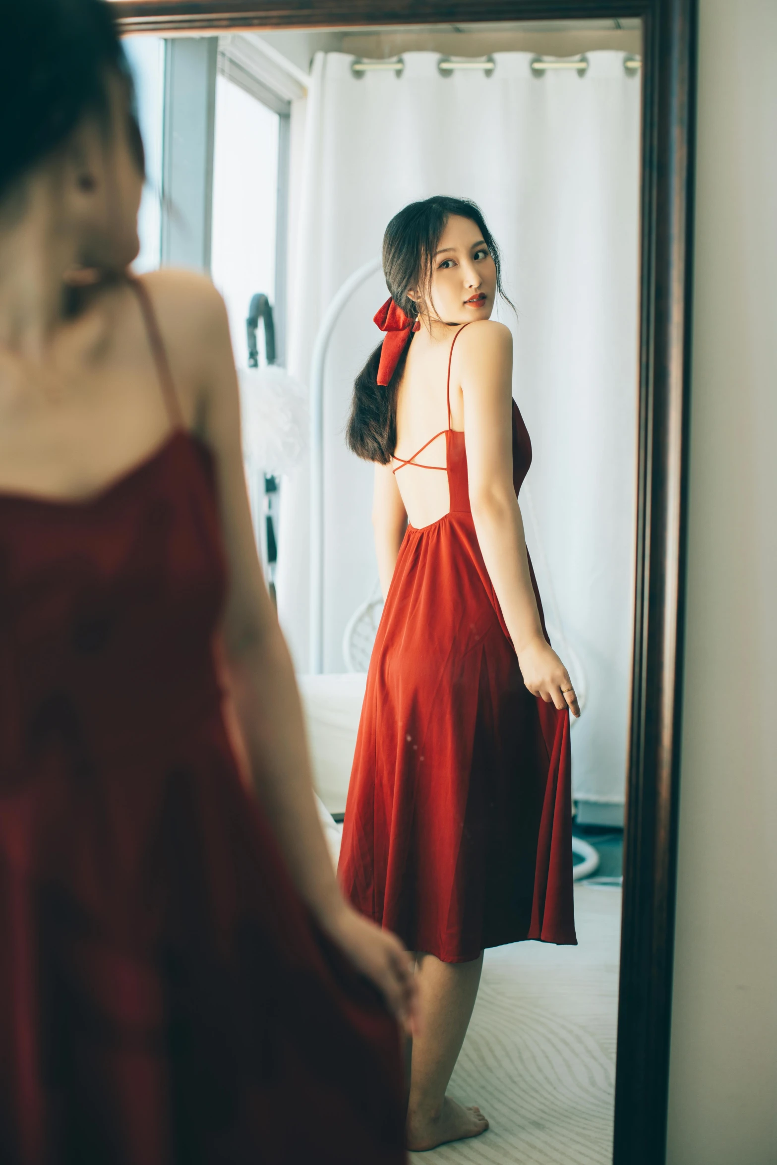  in red dress looking at herself in mirror