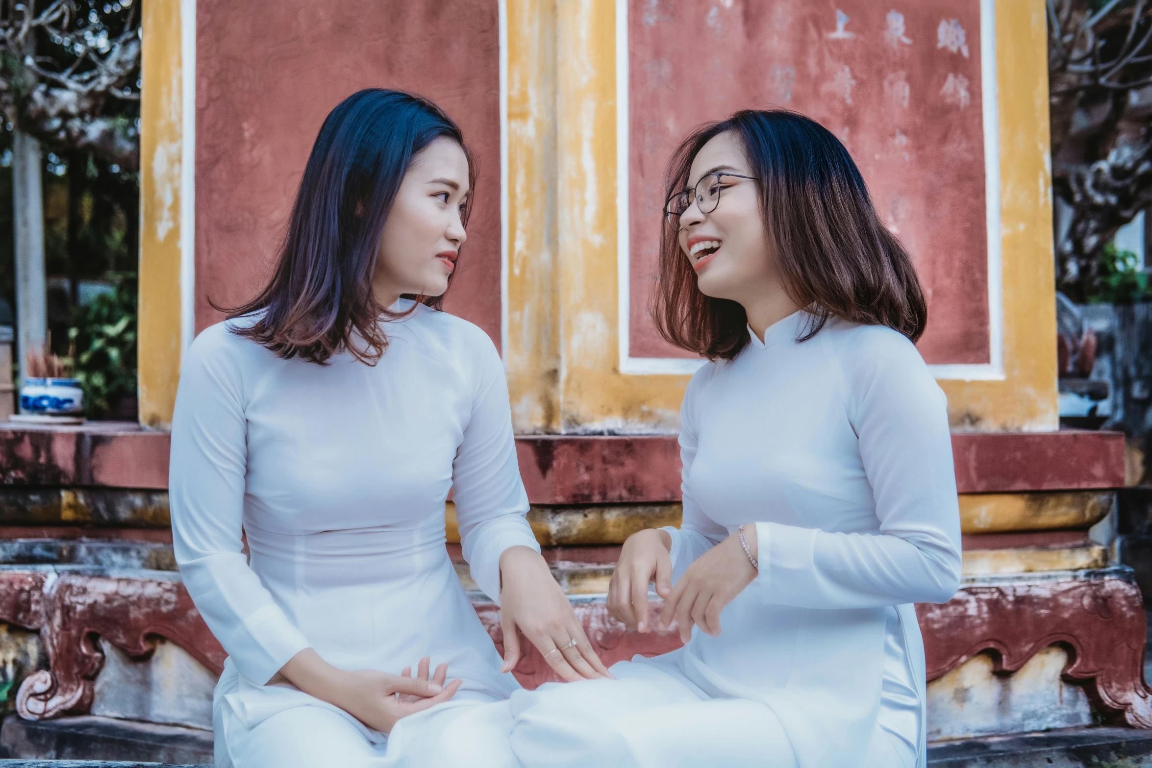 two young women sitting in front of a building