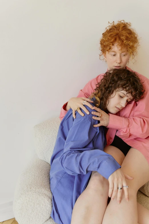 two women hug in a bedroom with a white wall