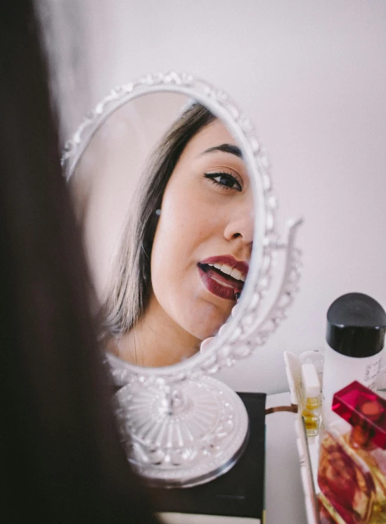 a woman is putting her lips in the mirror