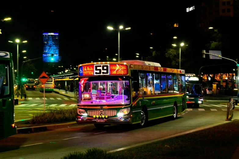 buses on the side of the road, driving around town at night