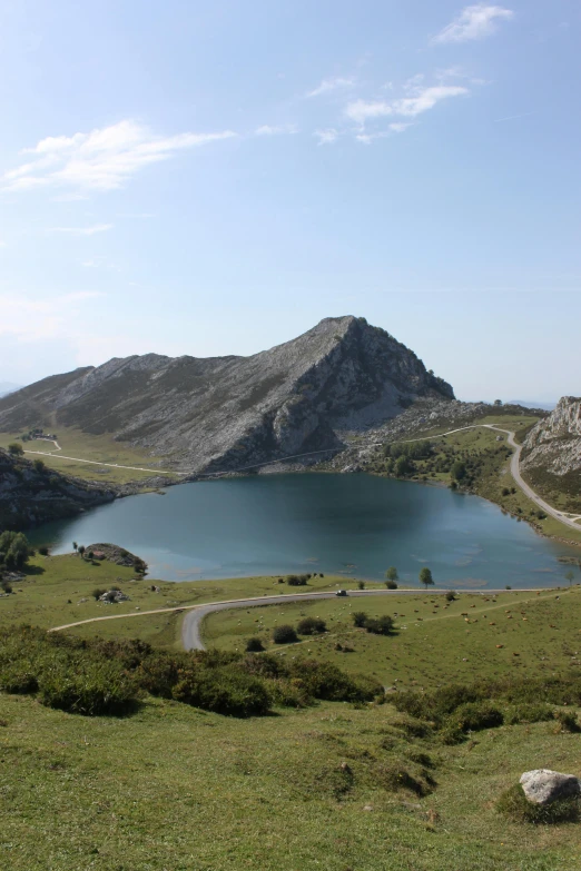 a grassy area with a large lake, road and hills