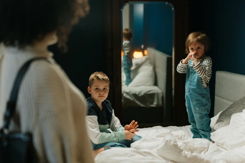 two small children stand on a bed as they brush their teeth