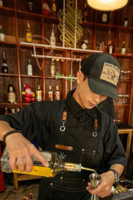 a man pours drinks from a bottle as he makes some sort of cocktail