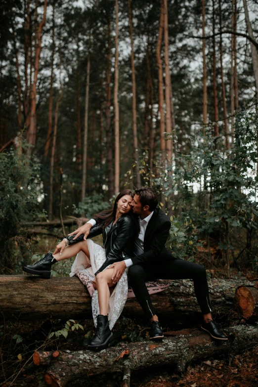 couple sitting on tree nch in forest with each other