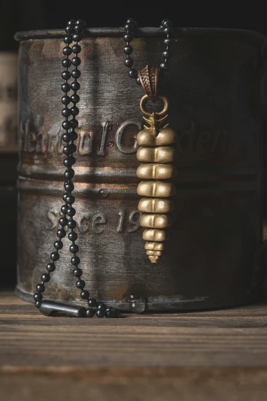 the long black beaded necklace has a gold tone pendant hanging from the side of it