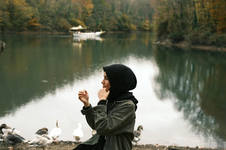 the woman is in a scarf sitting by the pond