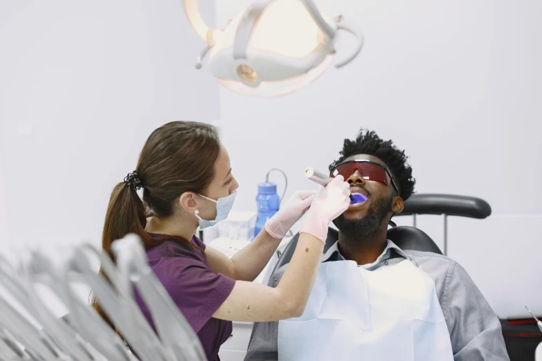 a woman is getting her teeth checked while a man sits in a dental chair