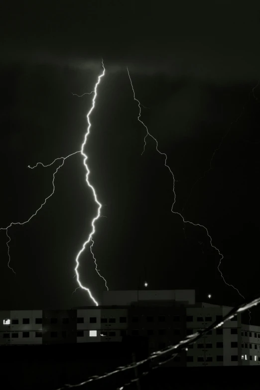 a very long lightning hitting on the building with dark sky