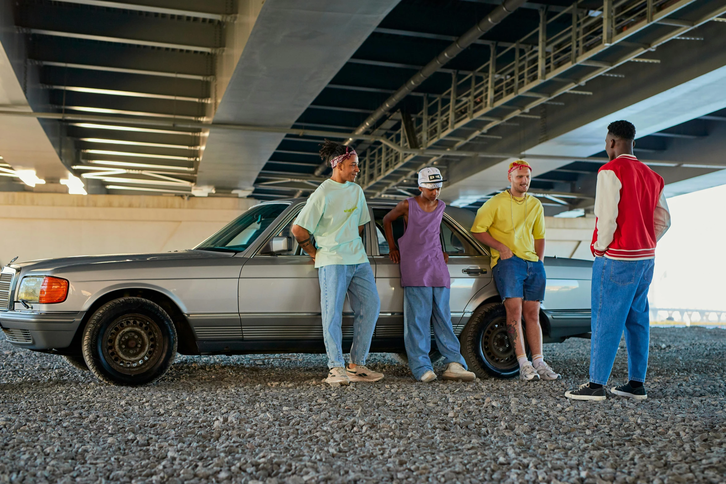 people standing in front of car under overpass next to roadway