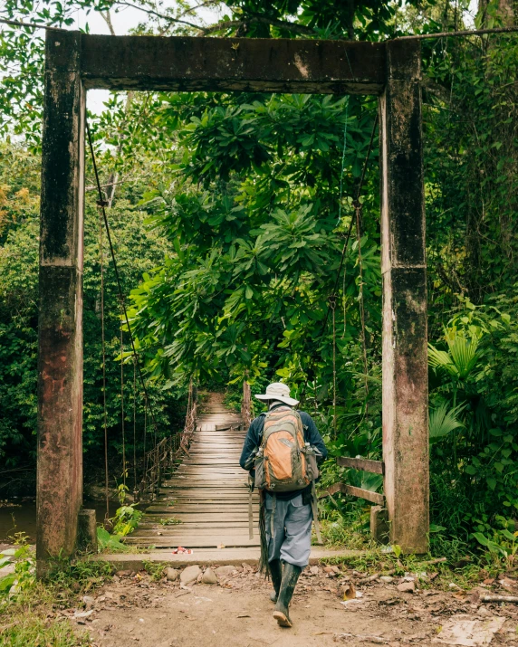 man with backpack walking over an old bridge