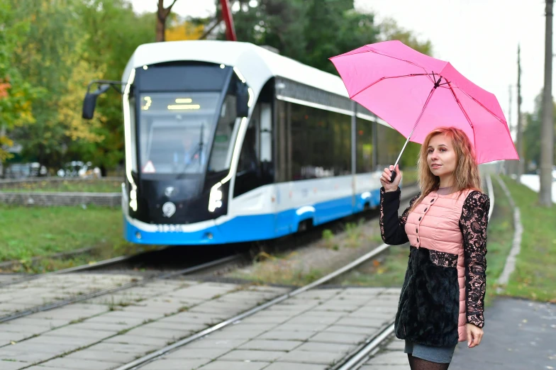 a woman holds an umbrella while a train passes by