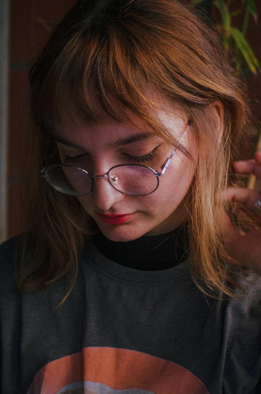 young woman with glasses and dark sweater looking at her phone